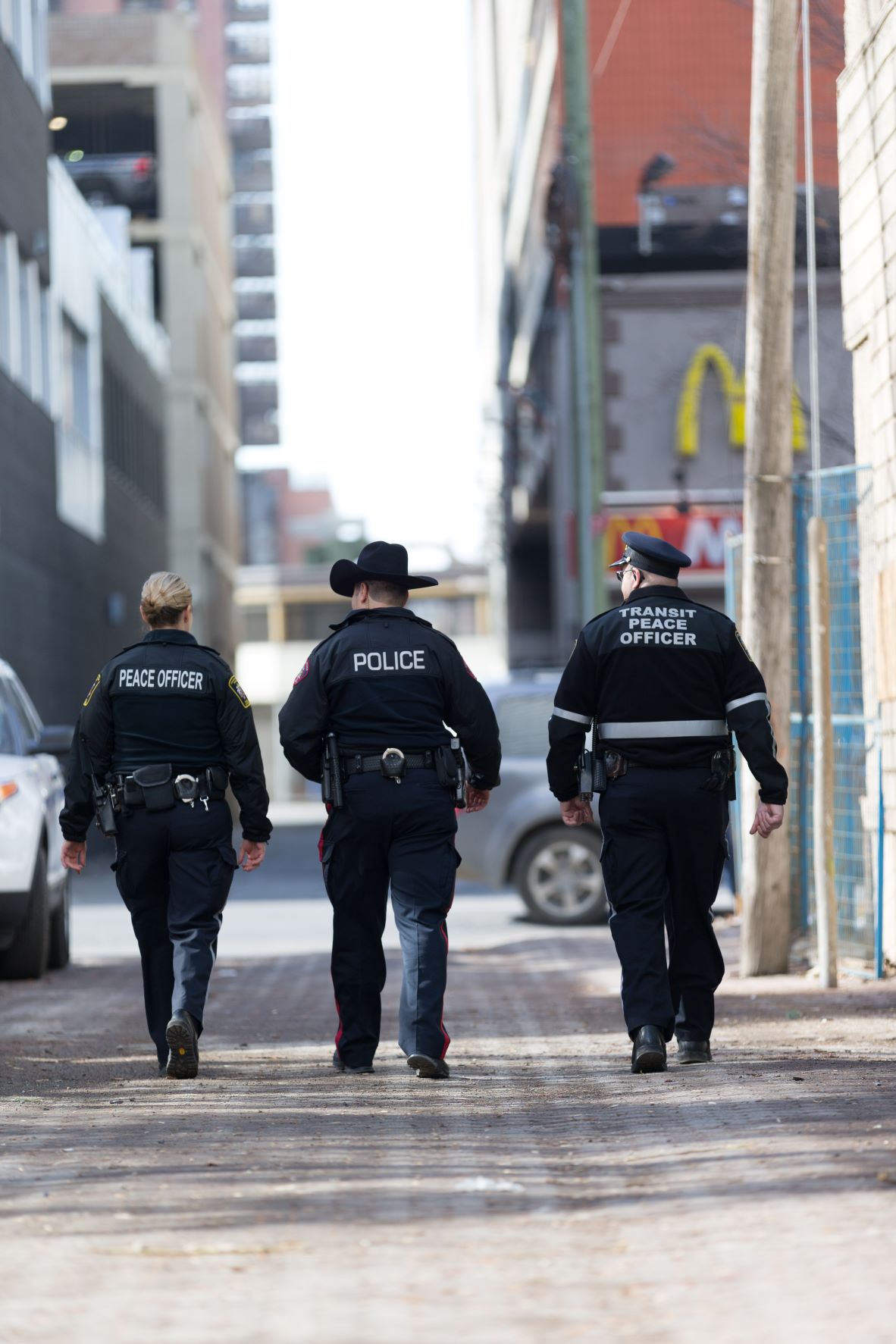 A Calgary peace officer, police officer and Transit peace officer walking side-by-side. 