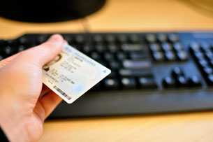 An individual holding onto a driver's licence over a keyboard.