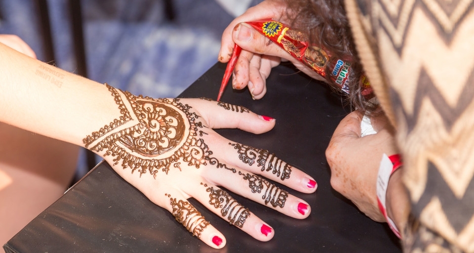 A person receiving a henna tattoo on the back of their hand