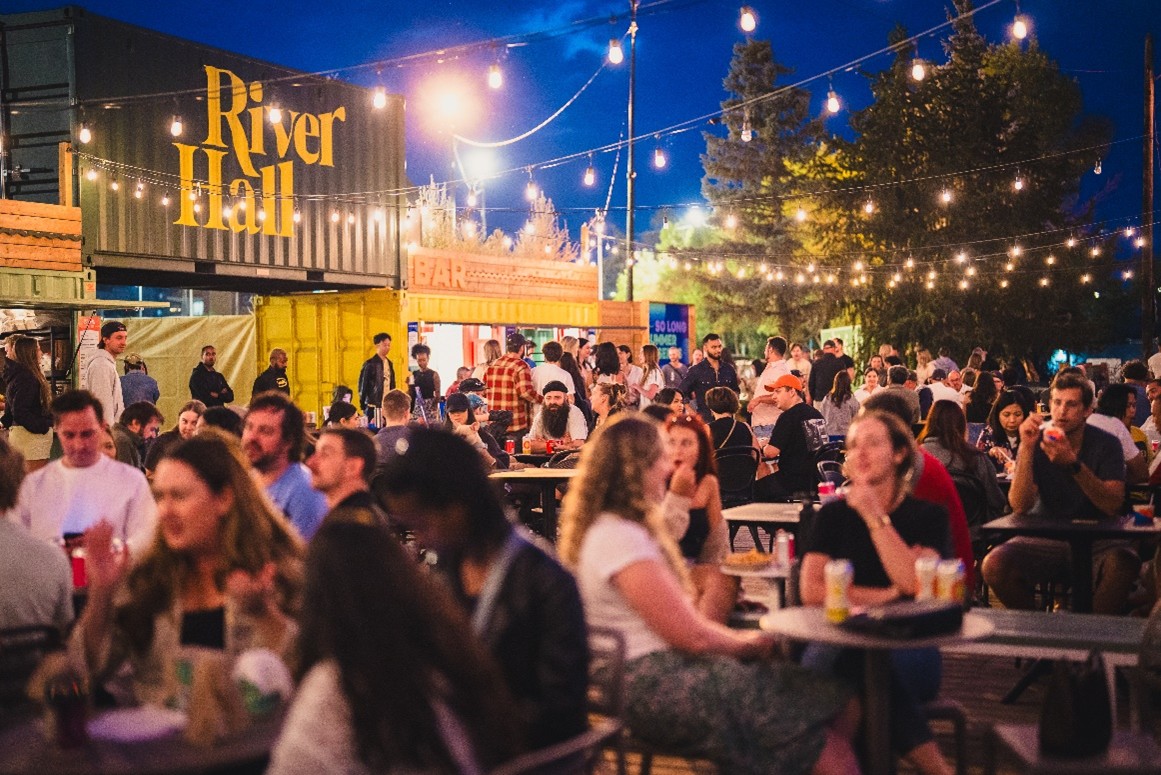 A man and woman sitting on yoga mats outside in the summer
