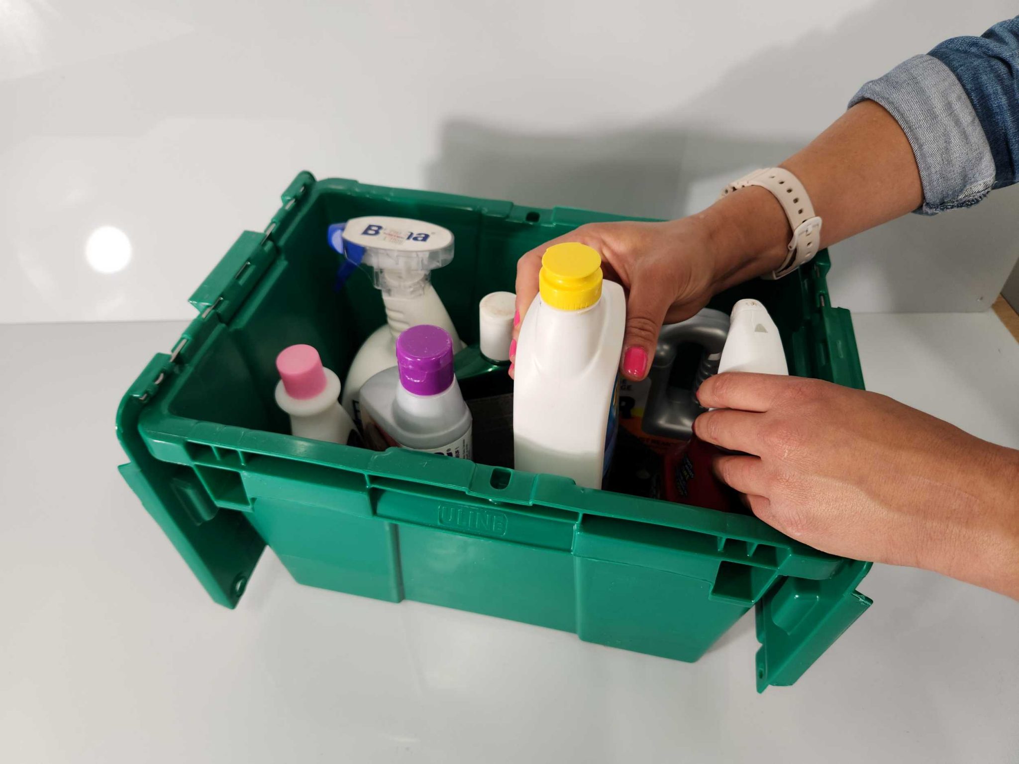 Person putting chemical bottle into a storage bucket with other chemicals.