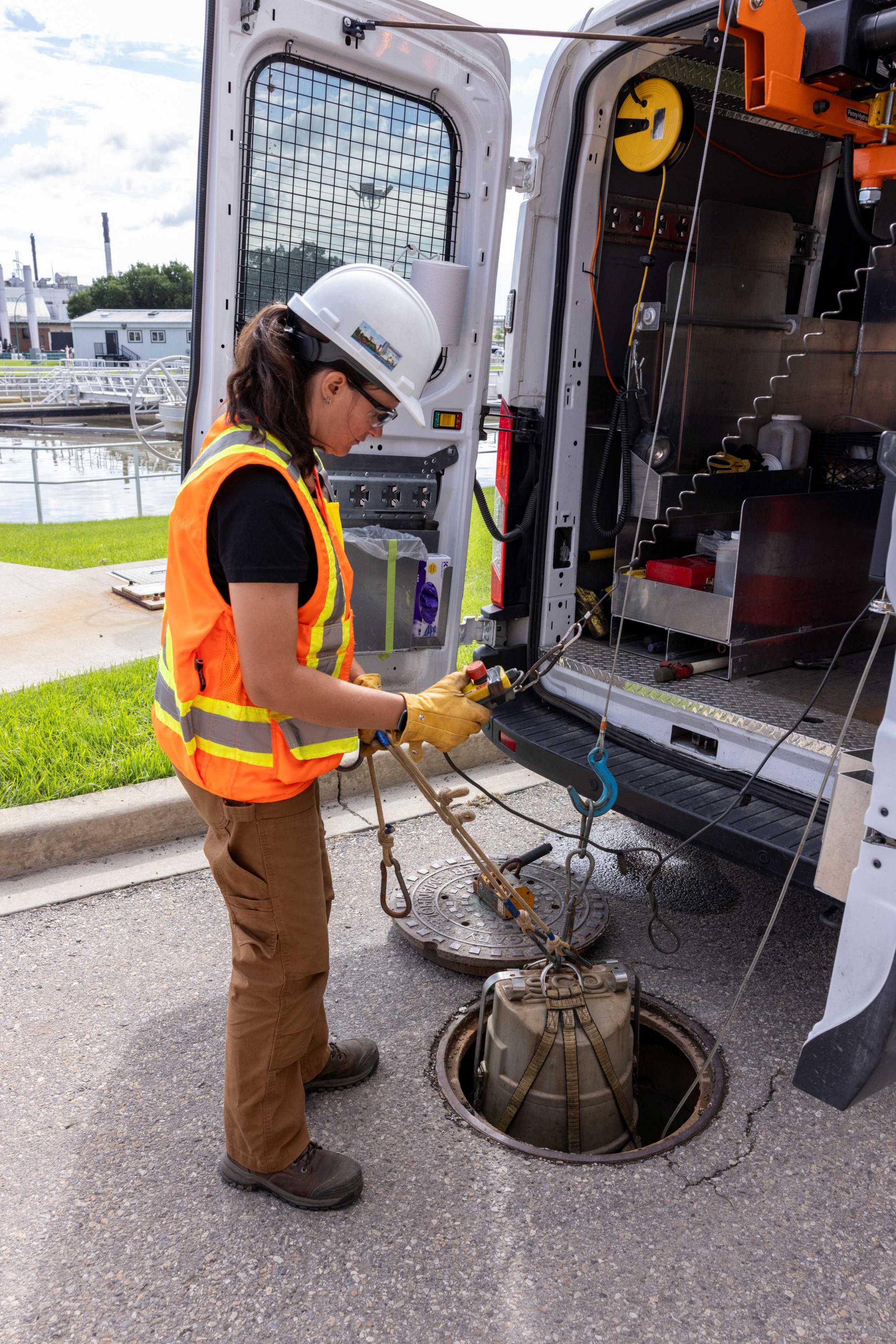 Individual taking a sample from a maintenance hole.