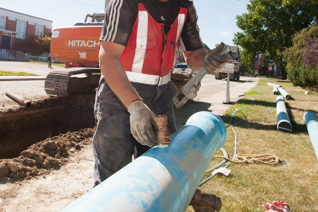 Construction worker fixing a blue water pipe because of a leak.